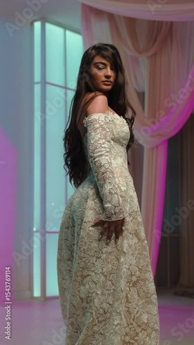 Elegant bride in intricately detailed wedding gown posing indoors