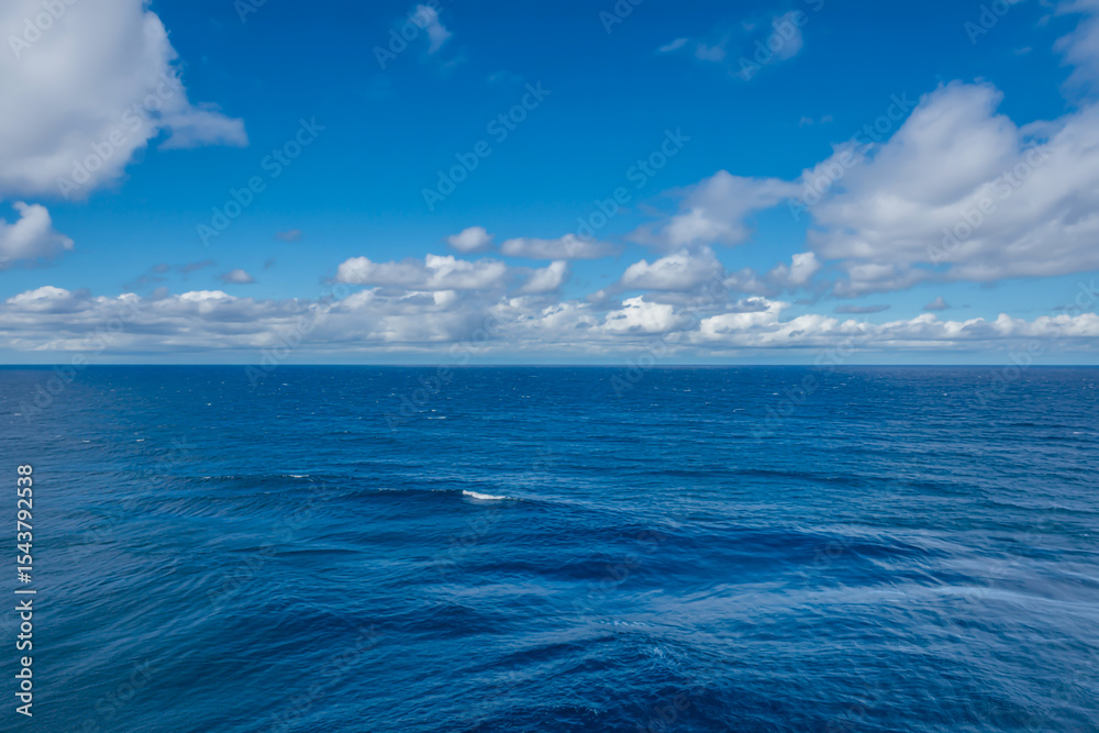 Obraz premium Vast Azure Horizon Mid-Day Seascape with Gentle Waves, Puffy Cumulus Clouds, and Dramatic Sky-Ocean Contrast in Sunlit Clarity