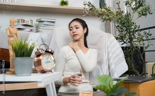 Self-care during moving. Woman relaxing with water and stretching her neck in a home setting.
