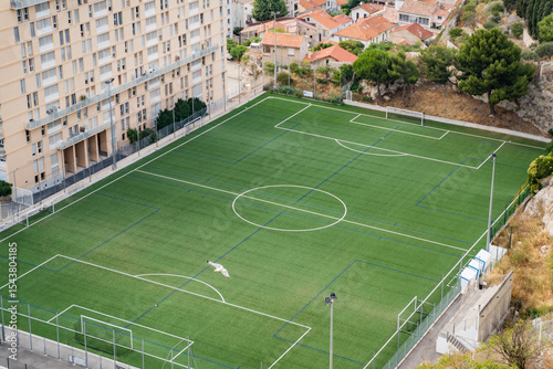 An aerial view captures a wellmaintained soccer field near an apartment building and homes surrounded by lush greenery
