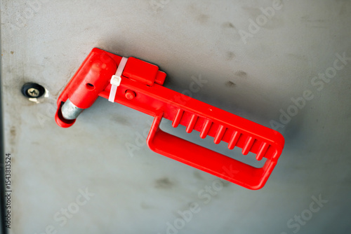 A red plastic handle that has a screw affixed to it firmly
