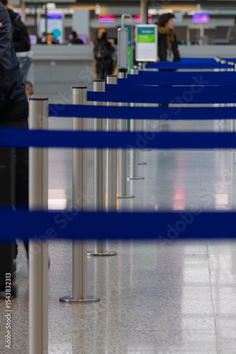 Metallic barrier poles with blue retractable belts in a row located in an airport terminal