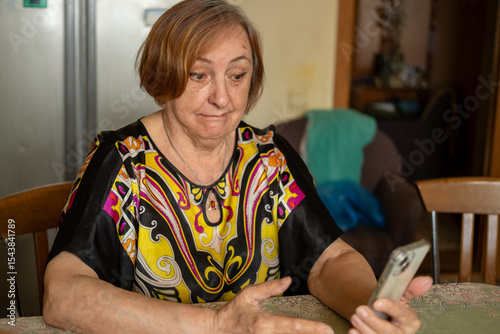 Happy elderly senior mature woman is using mobile phone, online video call talk with waving hand, greeting her relatives and grandchildren.