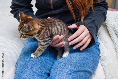 Child holding and caring for pet kitten at home