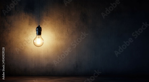 Glowing lightbulb against dark concrete wall, idea concept