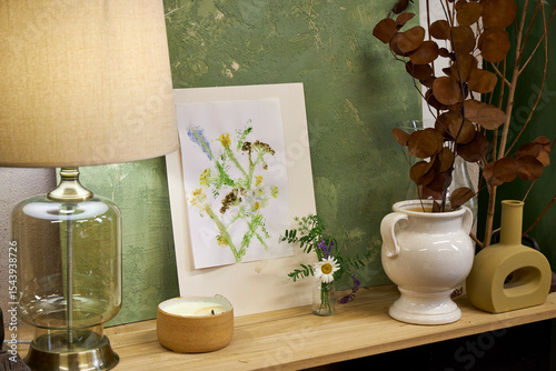 Finished botanical print displayed in cozy interior. Handmade floral artwork with wildflowers on shelf with natural home decor elements
