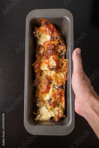 POV. Stuffed eggplant with meat and cheese in hand. 