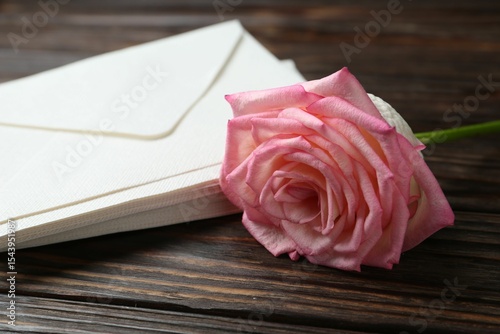 Stack of love letters and beautiful rose on wooden table, closeup