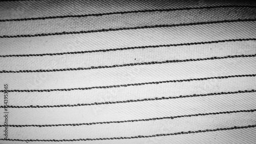 Extreme close-up of parallel dark stitching on white woven fabric. Clean, minimalist textile pattern. Great for textile design, craft blogs, and fashion industry backgrounds