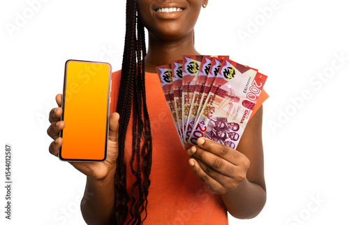 Beautiful Black woman lady smiling holding 200 Ghanaian cedi notes and showing pointing phone with blank screen to the camera over white background. Hand holding Ghanaian currency notes
