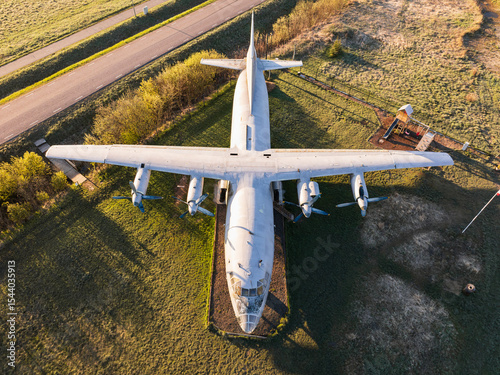 Drone view of an old, four-engine cargo airplane standing in a field at sunset as a monument to a bygone technological era.