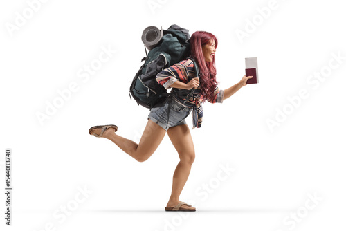 Full length profile shot of a young female traveler with a backpack running and holding a passport