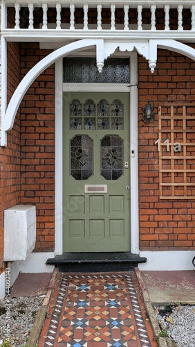 Old victorian wooden door with stained glass in a red brick wall, London