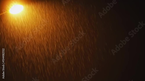 Abstract night scene featuring illuminated street lamp in focus during a rainfall