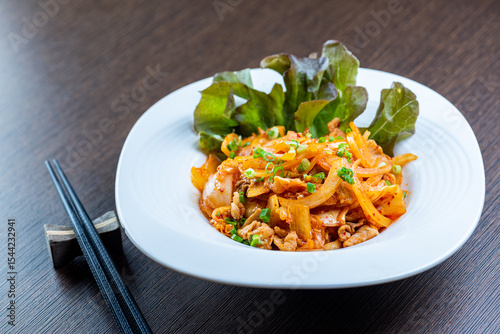 A plate of kimchi stir-fried with pork and served with lettuce.