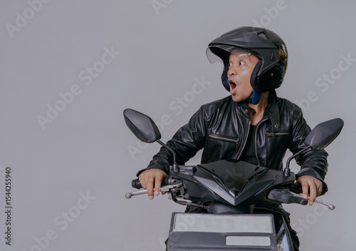 Shocked face expression of asian man wearing black leather jacket and helmet when riding a motorcycle, isolated on white background.