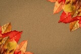 Clusters of autumn leaves are spreading across flat design textured brown paper surface corners