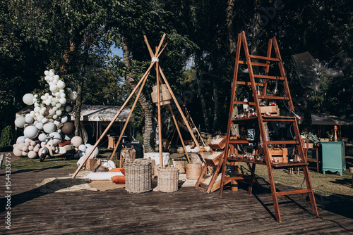 Wallpaper Mural Stylish boho-themed wedding setup with a tipi tent, wooden ladder shelf, and decorative baskets. Surrounded by trees, balloons, and cozy floor seating, ideal for outdoor celebrations. Torontodigital.ca