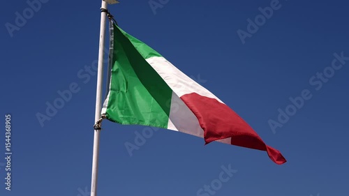 National flag of Italy waving in the wind against a clear blue sky