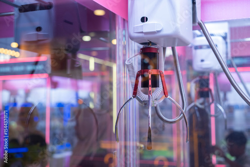 Close-up of a claw machine arcade with empty claws ready to grab prizes. Bright lights and colorful toys inside reflect the playful atmosphere of a modern game center or amusement park.