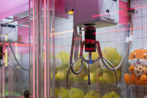 Claw machine close-up with plush toys inside, ready to be grabbed. The neon reflections and mechanical claw evoke a playful atmosphere of arcade gaming and prize hunting.