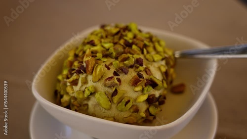 Creamy pistachio ice cream sprinkled with chopped pistachios, served in a white bowl, ready to be enjoyed