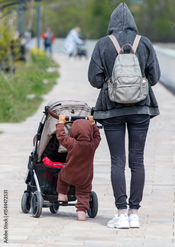 A woman is walking with a child in a stroller