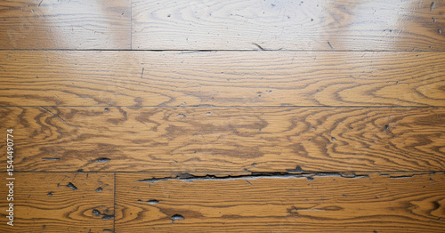 Worn golden wood surface with visible dents and scattered black marks, giving a vintage look and tactile detail under soft ambient daylight.