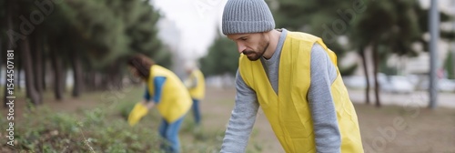 Young man in a beanie and yellow vest, Caucasian, meticulously planting saplings; celebrates National Arbor Day and Earth Stewardship