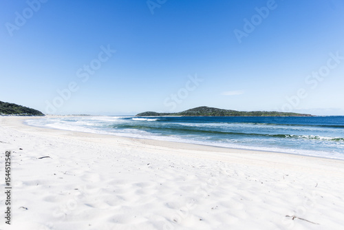 White sand beach meeting calm turquoise ocean water under blue sky