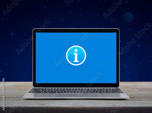 Information sign icon on modern laptop computer screen on wooden table over fantasy night sky and moon, Business customer service and support online concept