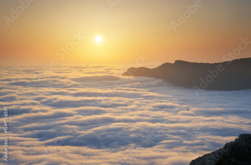 Mountain sunset over clouds.