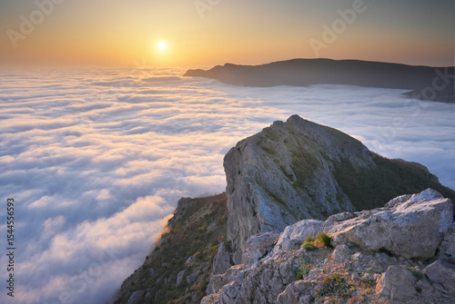 Mountain sunset over clouds.