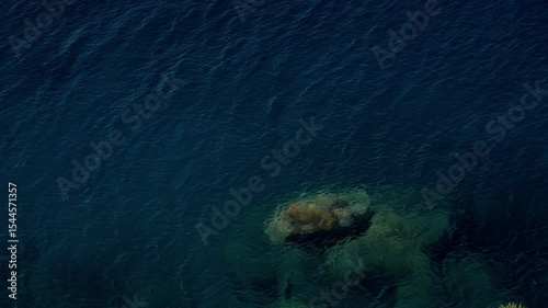 Dark blue rippled surface of the Tyrrhenian Sea with submerged rock in Scilla, Calabria, Southern Italy