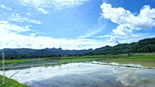 Nature's masterpiece. A 4K picturesque landscape times-lapse of rice paddies, mountains, and mirroring the vibrant sky clouds above.