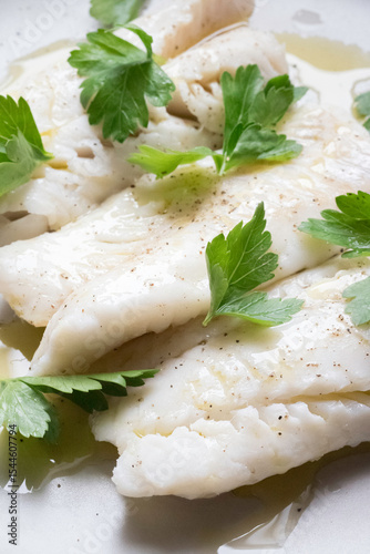 Dettaglio macro di filetto di pesce bianco condito con olio e prezzemolo fresco