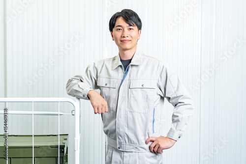 倉庫内で仕事をするカメラ目線の作業着を着た男性