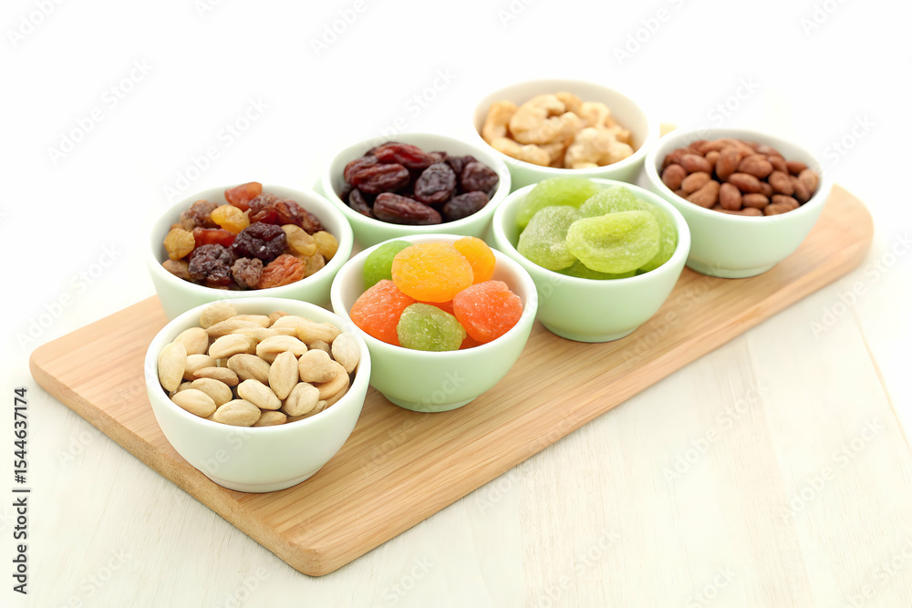 Assorted dried fruits and nuts in small ceramic bowls on wooden board Assorted dried fruits and nuts in small ceramic bowls on wooden board