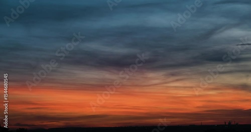 Timelapse of beautiful nightfall cloudscape scenery with beautiful bright orange glow in the sky slowly receding and clouds getting dark blue above flat countryside
