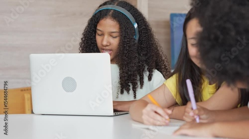 Diverse Girls Engaged in Digital Learning and Creative Activities, Teacher Guiding Students in a Modern Classroom Setting, Female Educator Assisting Students with Laptop and Homework