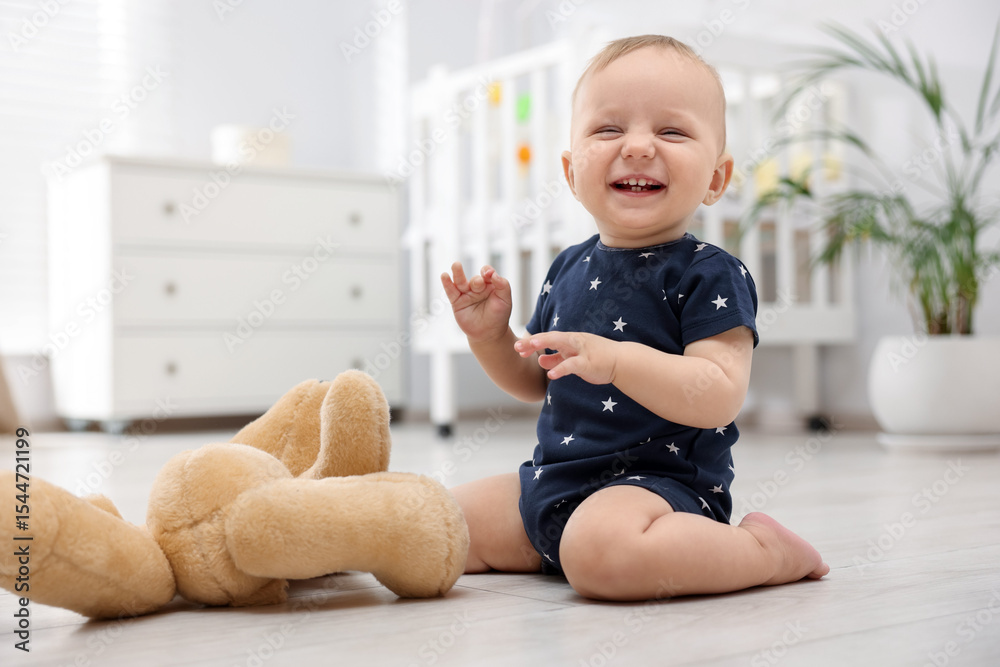 Naklejka premium Cute little baby playing with teddy bear in room