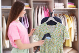 Smiling woman steaming dress on stand at home