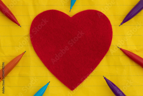 Colored pencils with yellow ruled loose leaf notebook paper with a heart