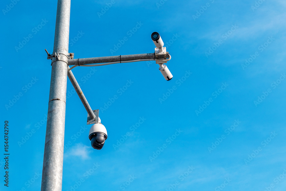 Fototapeta premium Security cameras mounted on pole against clear blue sky for surveillance
