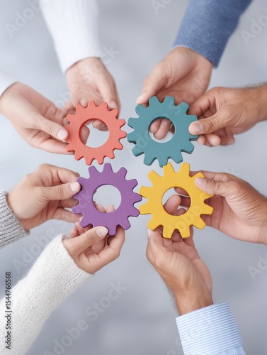 Multiple hands of varying ethnicities hold colorful gears, showcasing unity and cooperation. The soft-focus background enhances the vibrant colors and the connection among participants.
