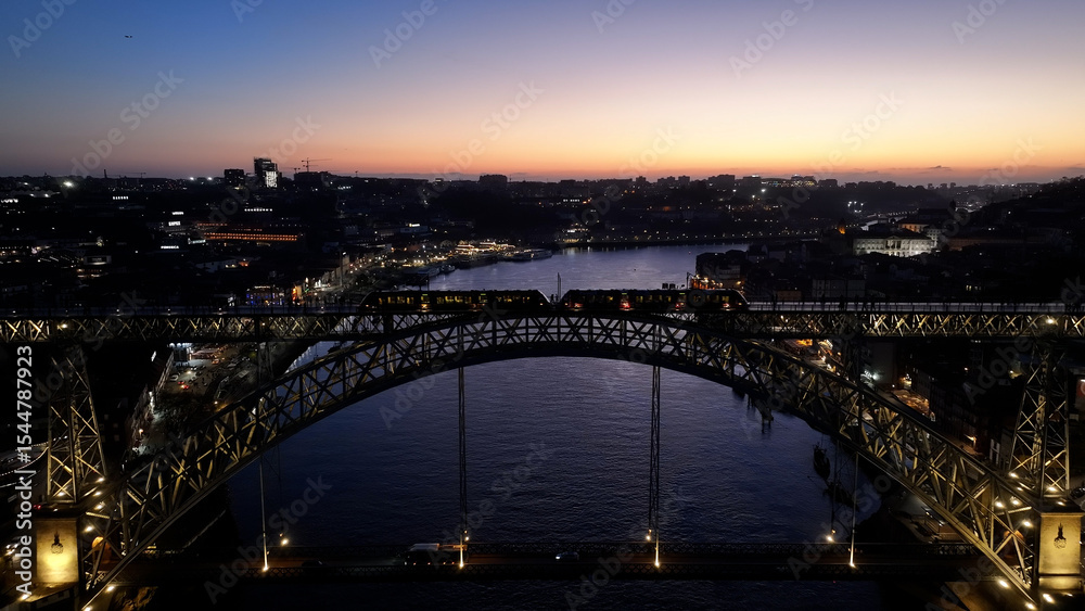 Fototapeta premium Sunset Luis I Bridge At Porto In Porto District Portugal. Sunset City Scene. Illuminated Bridge Landscape. Luis I Bridge At Porto District Portugal. Beautiful Dusk Skyline. 