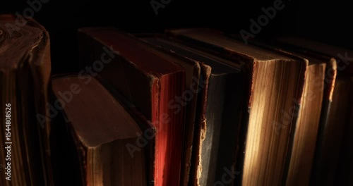 Stack of old antique books in a ray of light. Close-up view, slider macro 4K video.