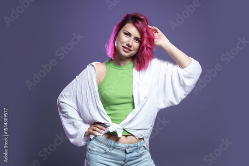 Beautiful woman with pink dyed hair on violet background