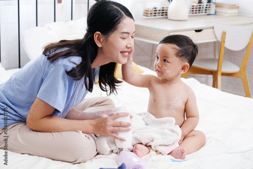 A mother gently applies powder to her baby on the bed, capturing a tender mother-and-child moment. A mother gently applies powder to her baby on the bed, capturing a tender mother-and-child moment.