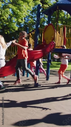 Vertical screen, multiethnic children running, jumping, and playing together with infectious joy on sunlit playground surrounded by verdant park landscape, showcasing pure childhood happiness